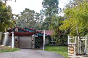 Fototapeta na wymiar Cute brick Australian house with tile roof and awning snuggled back into the tropical rainforest