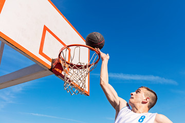 Slam Dunk. Side view of young basketball player making slam dunk