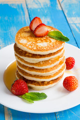 Stack of pancakes (fritters) with strawberries and honey on a plate.