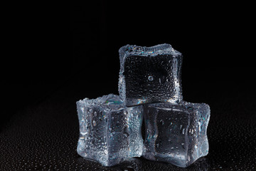 Cubes of clear ice on a black table.
