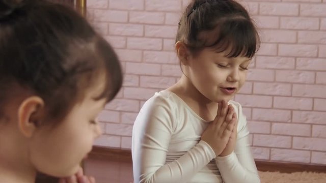 The girl prays before the mirror. The little dancer prays.