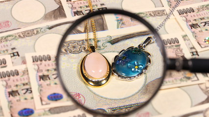 一万円札と拡大鏡と宝飾品
