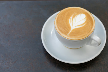 Top view of Hot Latte coffee with white cup and vintage black Iron table background