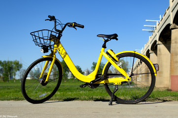 Fototapeta na wymiar Yellow Rental Bicycle parked on sidewalk