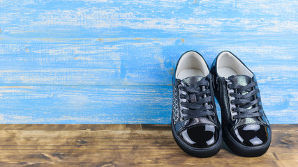 Black baby shoes sporty style on the wooden floor, the blue wall.