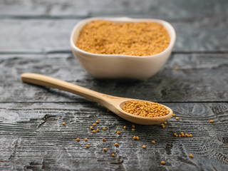 Spoon and Cup with mustard seeds on a dark wooden table.
