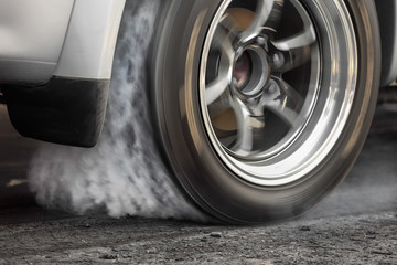 Une voiture de course de dragsters brûle le caoutchouc de ses pneus en préparation de la course