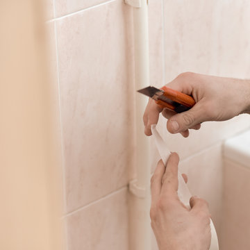 Closeup of man gluing adhesive tape on pipe in bathroom