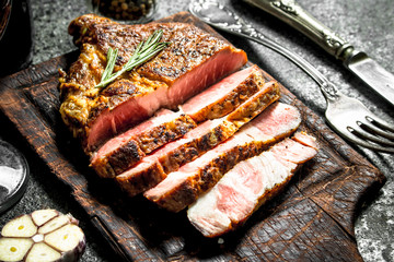 Grilled beef steak on a blackboard with spices.