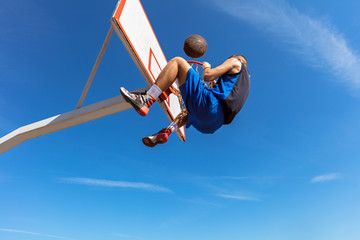 Slam Dunk. Side view of young basketball player making slam dunk