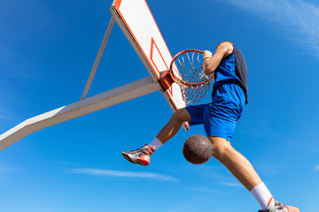 Slam Dunk. Side view of young basketball player making slam dunk