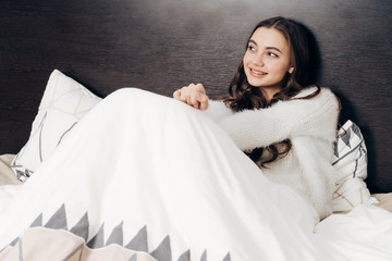 cute young girl is lying in bed, going to sleep, dreaming about something and smiling © mnelen.com