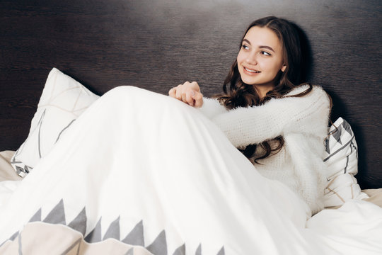 cute young girl is lying in bed, going to sleep, dreaming about something and smiling