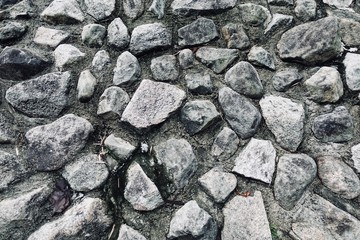 close up shot of texture of rough rock wall. Rough rocks are randomly placed to make a rock wall. Rock from mountain, unpolished. Abstract wall.