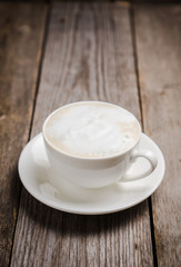 Sweet coffee latte in white cup on the rustic background. Selective focus.