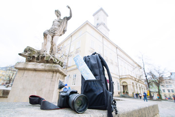 travel concept. camera map and backpack with blurred european town on background