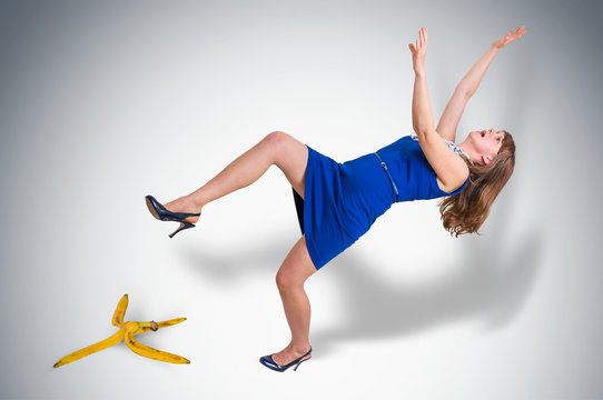 Business woman slipping and falling from a banana peel