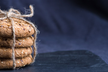 homemade oat cookies with sunflower seeds on shale board and dark blue textile background