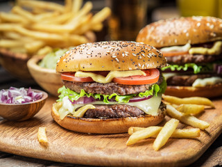 Hamburgers and French fries on the wooden tray.