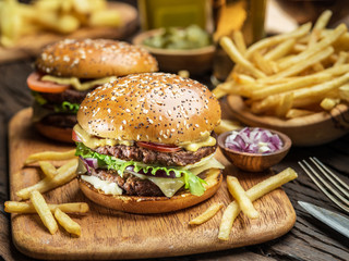Hamburgers and French fries on the wooden tray.