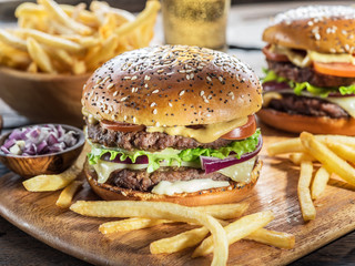 Hamburgers and French fries on the wooden tray.