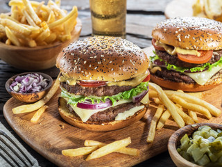 Hamburgers and French fries on the wooden tray.