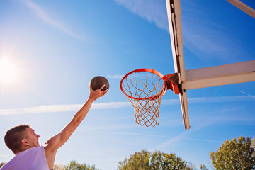 Slam Dunk. Side view of young basketball player making slam dunk