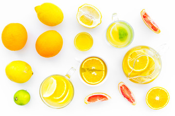 Fruit tea. Teacup and teapot among citrus on white background top view