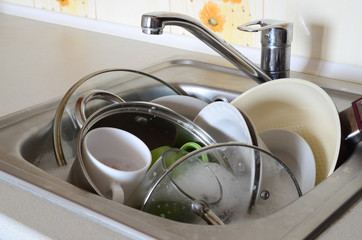 Dirty dishes and unwashed kitchen appliances filled the kitchen sink © mehaniq41