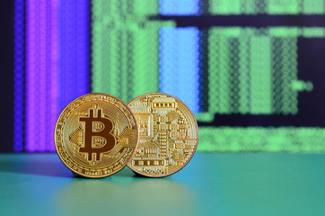 Two gold bitcoins lie on the green surface on the background of the display, which shows the...