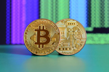 Two gold bitcoins lie on the green surface on the background of the display, which shows the...