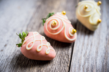 Ripe strawberry with chocolate glaze on the wooden background. Selective focus.