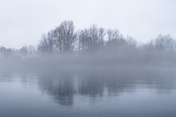 Obraz na płótnie Canvas Dramatic background of foggy weather at the lake