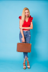 Summer, fashion and holiday concept - Beautiful blonde woman with retro suitcase on blue background