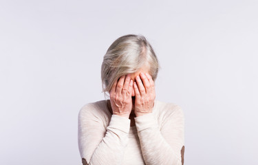 Studio portrait of a senior woman in pain.