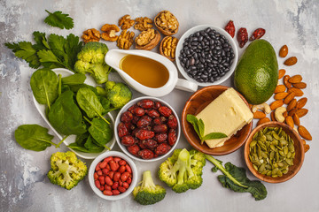 Healthy food nutrition dieting concept. Assortment of high vitamin E sources. Oil, nuts, avocado, butter, healthy fats, rose hips, parsley, seeds, spinach. White backgdound, top view