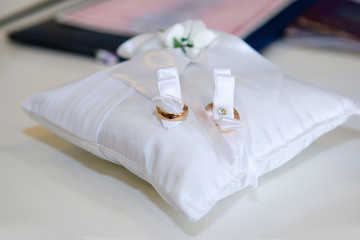 Fototapeta na wymiar Wedding gold rings on the pillow close. The symbol of the marriage of the bride and groom.