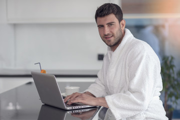 A man in a robe with a laptop at home