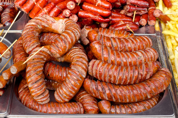 Fototapeta premium assorted sausages grilled on skewers on a large plate, mushrooms on the grill. Street festival food.
