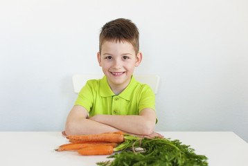 Closeup of adorable young boy with carrot. White background