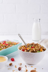 Baked granola in the baking tray  and  white ceramic bowl with various delicious ingredients for healthy breakfast