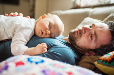 Father with a sleeping baby girl at home.
