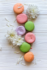 Obraz na płótnie Canvas Close up colorful macaroons and flower on white wood background. Flat lay