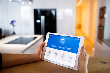 Male hands holding a tablet with smart home screen.