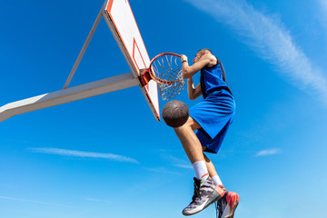 Slam Dunk. Side view of young basketball player making slam dunk © FS-Stock