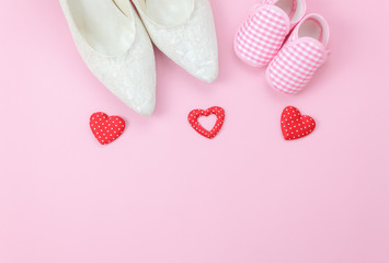 Top view aerial image of decoration Happy mothers day holiday background or women & kid fashion concept.Flat lay shoe woman and baby on modern beautiful  pink paper and red heart.Free space for text.