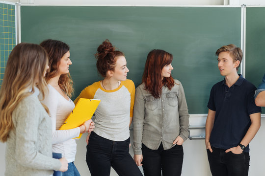 Group of students talking against blackboard