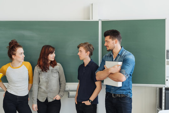 Group of students talking with teacher in class