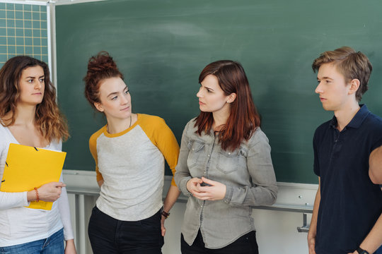 Students talking in classroom against blackboard