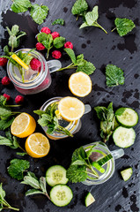 Home made mojito, Cucumber, lemon and raspberry fresh drink with fruits and vegetable on black background. 